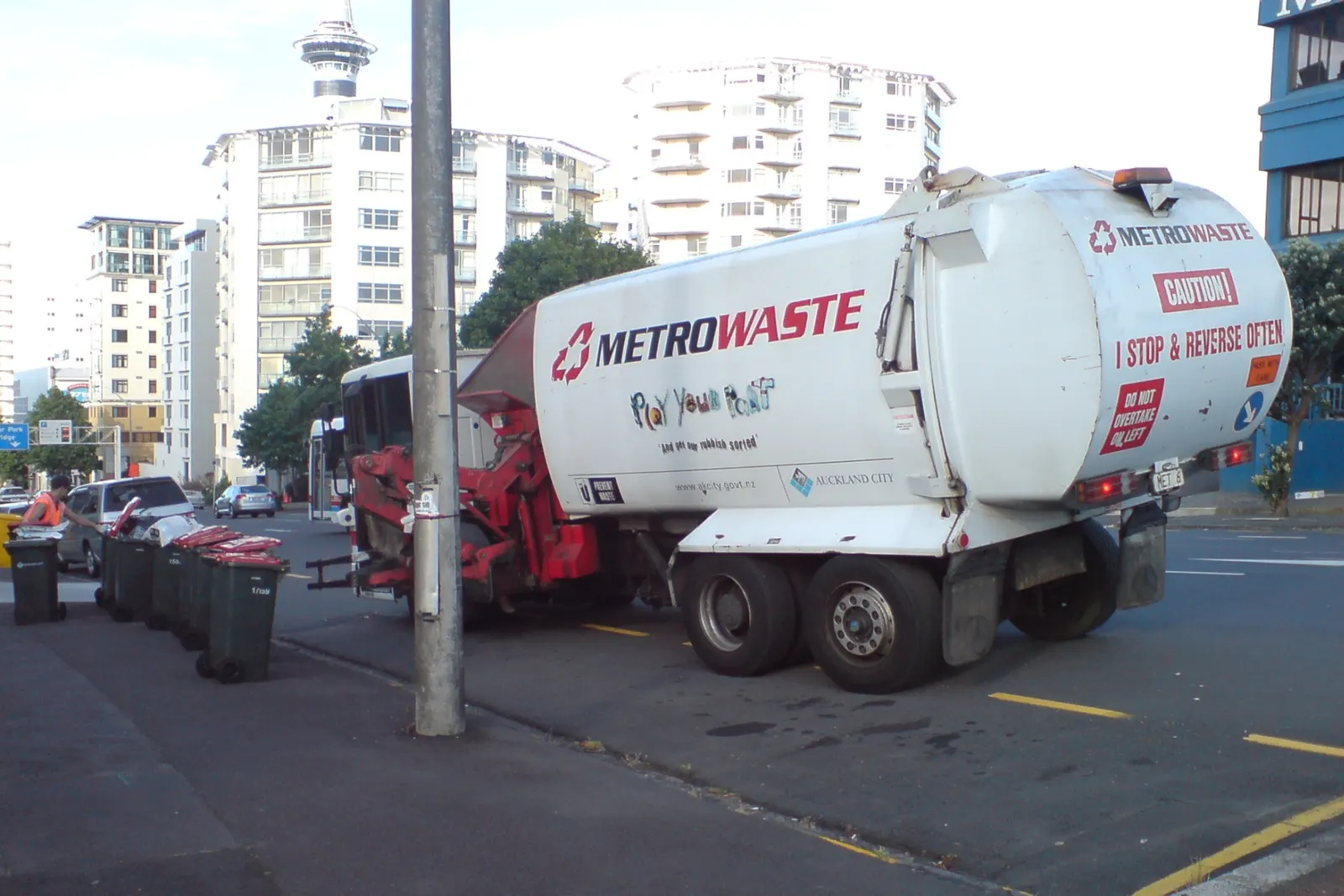 A waste collection truck working a kerbside route in a city street