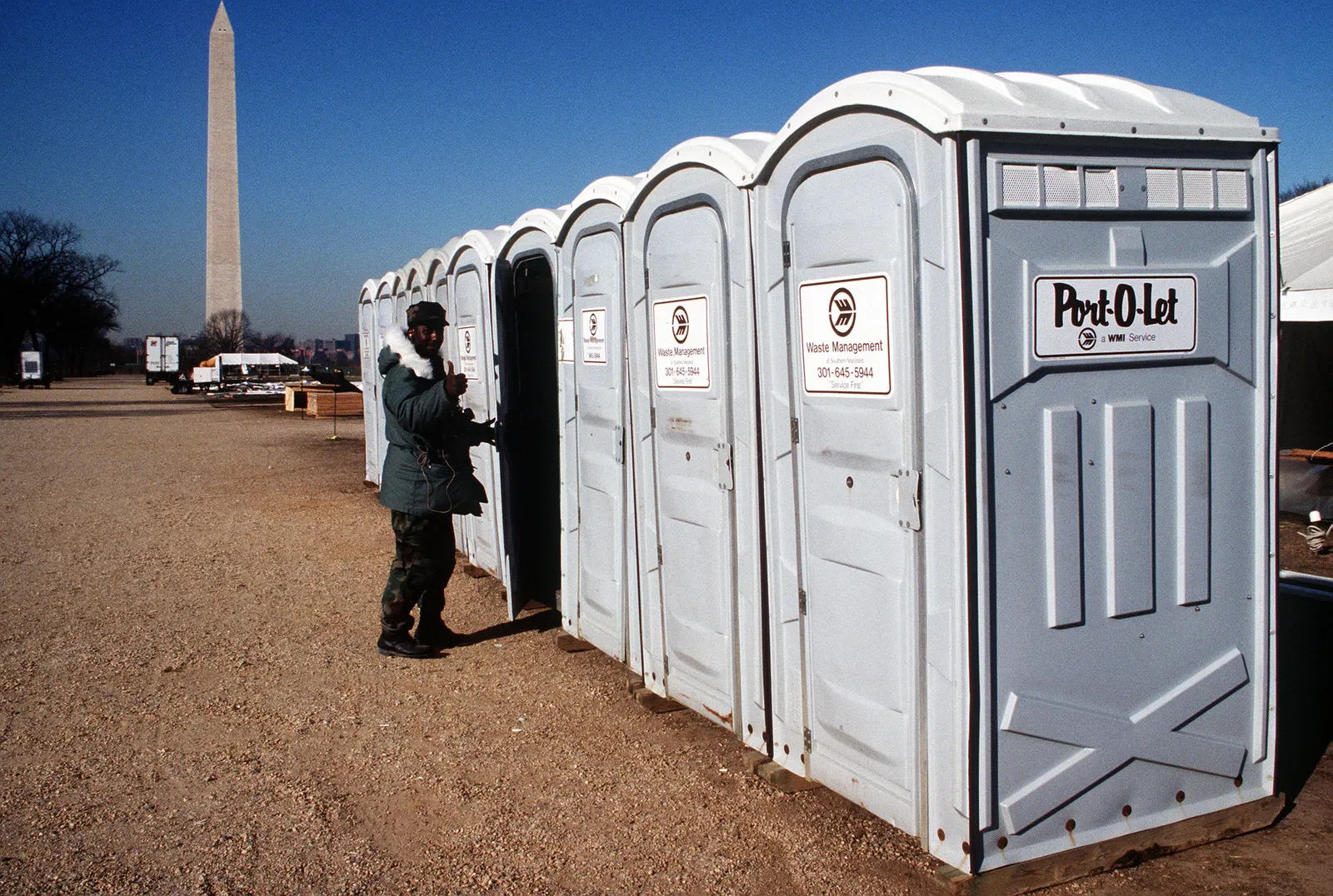 A row of portable toilet units set up on open ground for a large public event